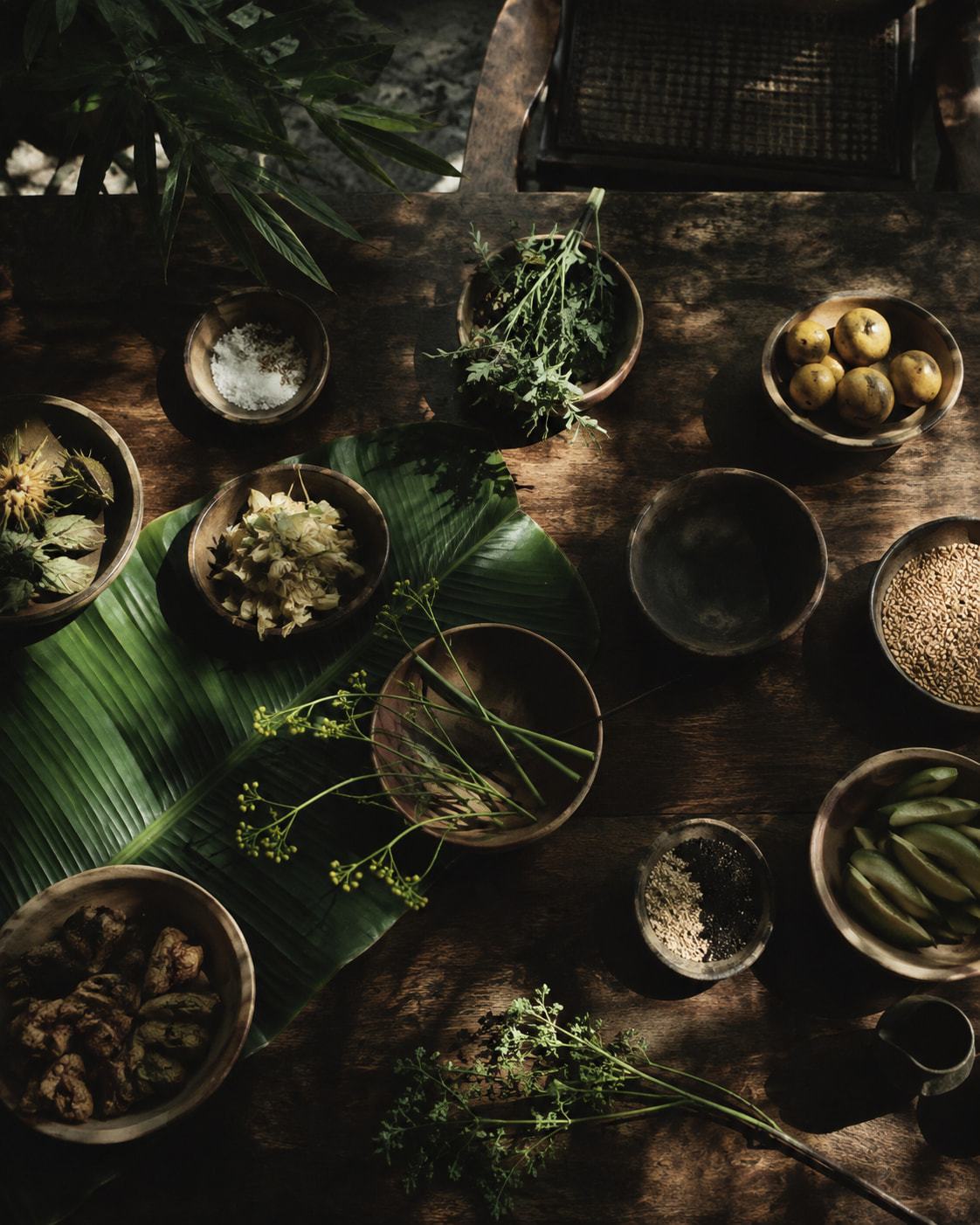 Overhead table of clay bowls, spices and banana leaf